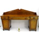 A William IV mahogany breakfront sideboard with raised triangular pediment and scrolling supports,