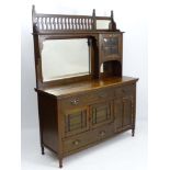 Arts and Crafts: An early 20thC sideboard with raised back gallery beside a small mirror,