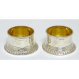 A pair of silver circular salts with gadrooned base and gilded interiors.