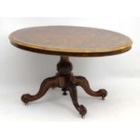 A Victorian burr walnut loo table with an oval tilt top and carved acanthus pedestal base standing