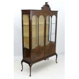 An early 20thC mahogany display cabinet with half circle and keystone style pediment,