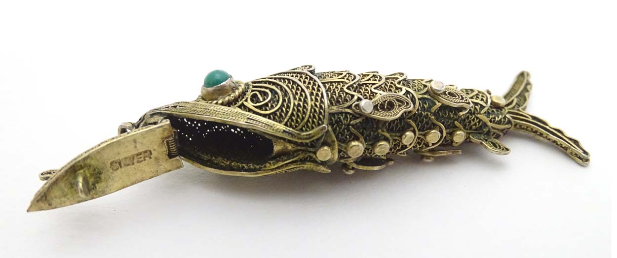 A silver gilt pendant formed as an articulated fish with green stone eyes hinging open to reveal - Image 5 of 6