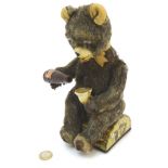 A c1950s Alps mechanical picnic bear sitting on a log drinking,