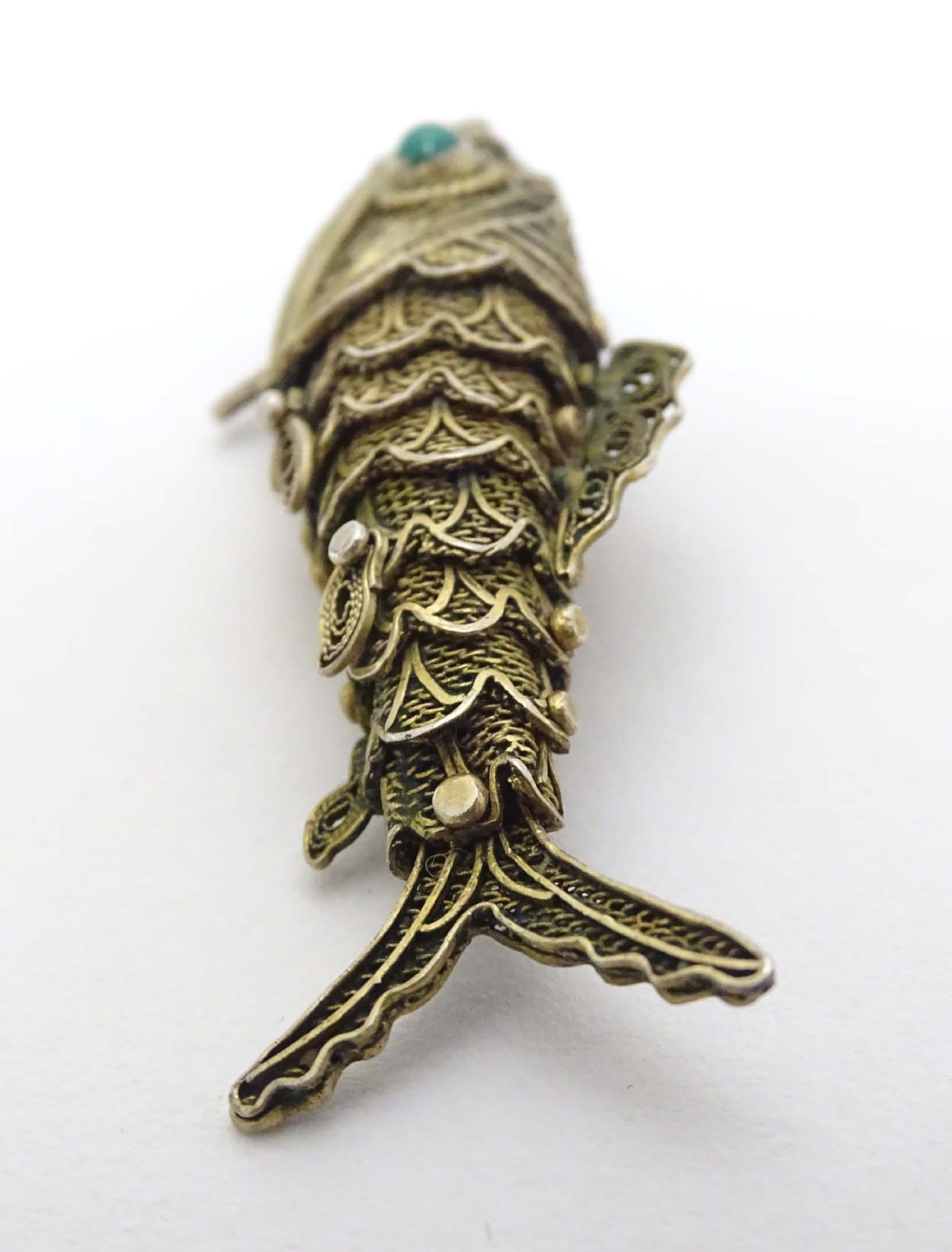 A silver gilt pendant formed as an articulated fish with green stone eyes hinging open to reveal - Image 2 of 6