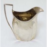 A silver milk jug with reeded decoration.