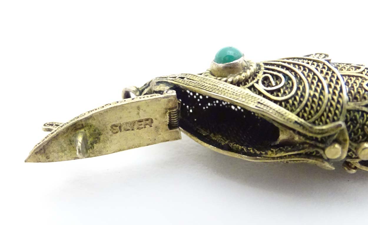 A silver gilt pendant formed as an articulated fish with green stone eyes hinging open to reveal - Image 6 of 6