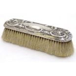 A silver backed brush with embossed decoration.