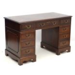 A mid 20thC mahogany pedestal desk, with eight short draws and one long,