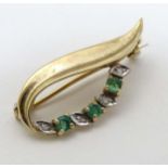 A 9ct gold brooch with green and white stone and leaf decoration. Hallmarked London 1988 maker SJ.