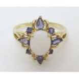 A 14ct gold ring set with central opal cabochon bordered by purple stones.