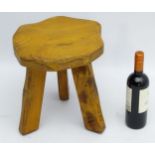 A mid 20thC elm three legged milking stool. Stamped under “Wanderwood”. 13 ¼” high x 13” wide.