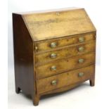 A Georgian oak bureau with four long drawers and a drop-down section opening to reveal fitted