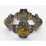 A silver bracelet with filigree like decoration set with Tigers Eye cabochons.