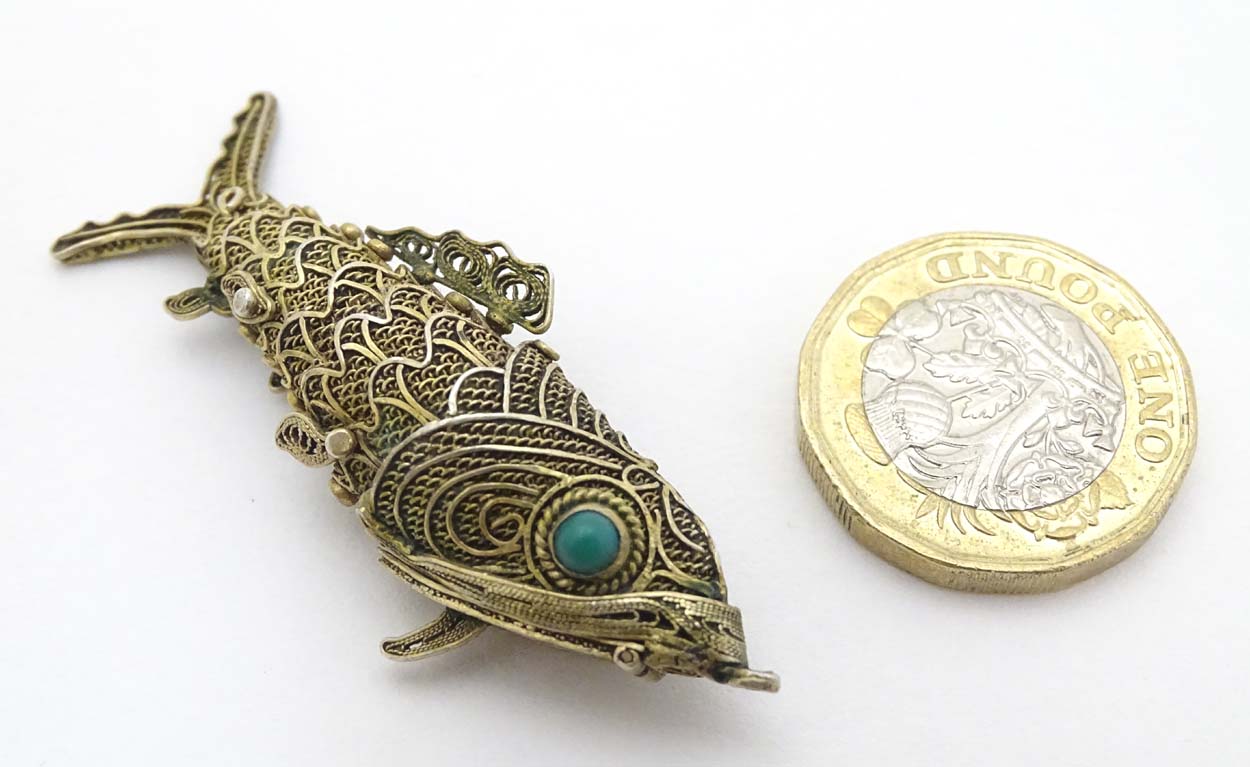 A silver gilt pendant formed as an articulated fish with green stone eyes hinging open to reveal - Image 3 of 6