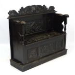 A late Victorian ebonised oak settle with lion's paw arm rests,