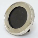 A photograph frame of circular form with silver surround hallmarked London 1919 maker William Henry