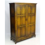 A mid 20thC oak two door compactum wardrobe with panelled front and sides,