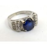 A white gold ring set with large central sapphire flanked by diamonds CONDITION: