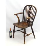 A 19thC elm and ash Windsor wheel back chair, with swept arms and supports,