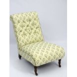 An Edwardian button back nursing chair with floral upholstery standing on ring turned front legs