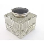 A cut glass inkwell of squared form with silver mounts and inset Bakelite roundel to lid.