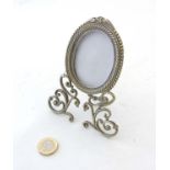 A late Victorian nickel oval photograph frame with ornate 3-footed base.