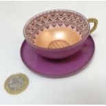 A small pink enamelled teacup and saucer on metal,