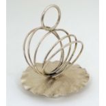 A silver plate 4-slice toast rack on shaped circular base reminiscent of work by Dr Christopher