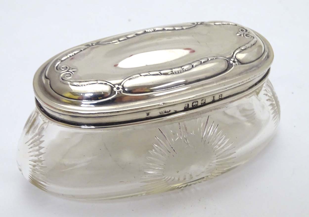 A glass dressing table pot with cut roundel decoration and silver lid hallmarked Birmingham 1910