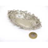 A silver bon bon dish with embossed floral and C-scroll decoration.