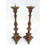 A pair of 18thC / 19thC fruit wood triangular based Continental? brass candlesticks / pricket stand