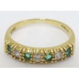 An 18ct gold half eternity ring set with green and white stones CONDITION: Please