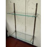 A pair of late 20thC brass wall brackets supporting two glass shelves. 18" wide x 29" high.