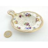 A 19thC Dresden style hand painted porcelain tea strainer decorated with flowers and having gilt