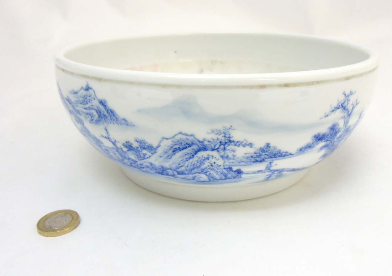 A Chinese blue and white bowl decorated in an underglaze blue continuous landscape and iron red