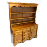 A mid 19thC oak and mahogany west country dresser, with three tier plate rack below a shaped frieze,