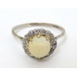 A white metal ring set with central opal bordered by diamonds CONDITION: Please Note