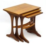 Vintage Retro : A nest of three teak graduated tables with trestle ends and bowed stretcher,