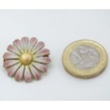 A vintage gilt metal brooch formed as a daisy flower head with enamel decoration .