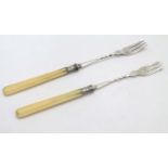 A pair of silver pickle forks with ivory handles.