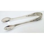 Silver sugar tongs with scroll decoration.