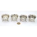 A set of 4 silver salts each with three legs and flared rims.