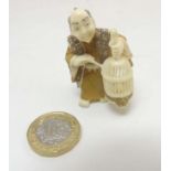 A Japanese meiji period signed and coloured netsuke formed as a figure holding a bird within a cage.