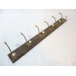 A set of 6 Victorian brass coat hooks with porcelain ends on a wooden mount.