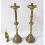 A pair of Late Victorian tall weighted Gothic brass candle sticks, on four short feet.