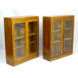 A mid 20thC pair of oak bookcases with adjustable shelves and glazed doors.