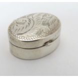 A small silver pill box with engraved decoration to lid.