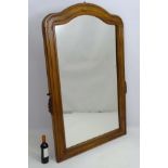 A mid 20thC walnut mirror of large proportions, with applied carving to each side of the face.