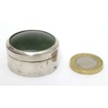 A hallmarked silver pill box of circular form with green hard stone cabochon to top.