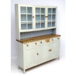 An early 20thC oak Heals cottage dresser with glazed top containing shelves within,